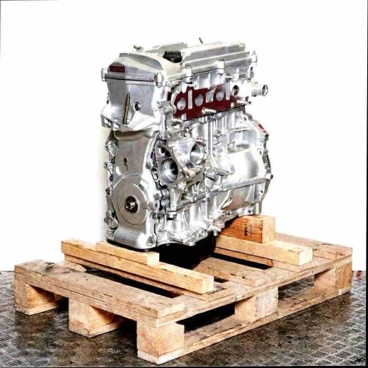 Silver 1AZ-FSE engine on a wooden pallet against a white background. Side view of the engine, vertically oriented.