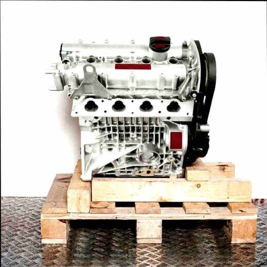 Silver APE engine on a wooden pallet against a white background. The engine, featuring black belts and a cover, is shown vertically.