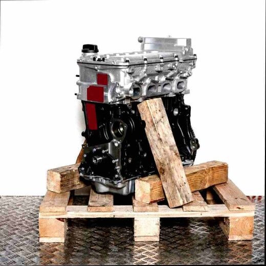 BKJ engine on a wooden pallet against a white background. This image features a black and silver engine, vertically oriented.