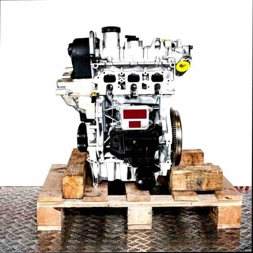 Side view of the DKJA engine on a wooden pallet against a white background. The silver and black engine with yellow accents is vertically aligned.