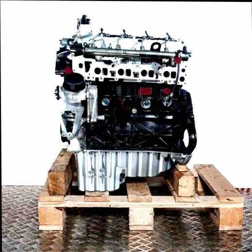 Black and silver engine OM 646.990 on a wooden pallet against a white background. Side view of the engine with yellow caps.