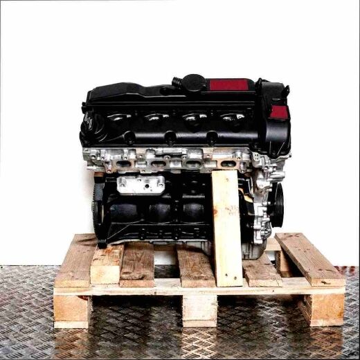 Side view of engine OM 651.955 on a wooden pallet against a white background. The engine block is black, the top part is silver.