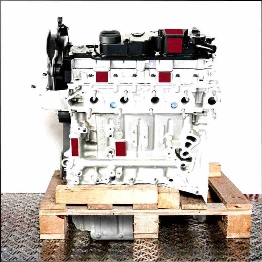 T1BB engine on a wooden pallet against a white background. The engine block, made of light gray metal with black plastic covers, is visible.